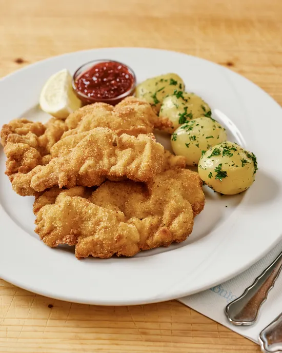 Knuspriges Wiener Schnitzel mit Petersilienkartoffeln, Zitronenscheiben und Preiselbeersoße